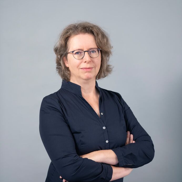 Hämatopathologie Lübeck - Dr. med. Ulrika Maria Schade - Fachärztin für Pathologie Porträt von Dr. med. Ulrika Maria Schade. Sie trägt eine dunkelblaue Bluse, eine Brille und posiert mit verschränkten Armen vor einem neutralen Hintergrund.