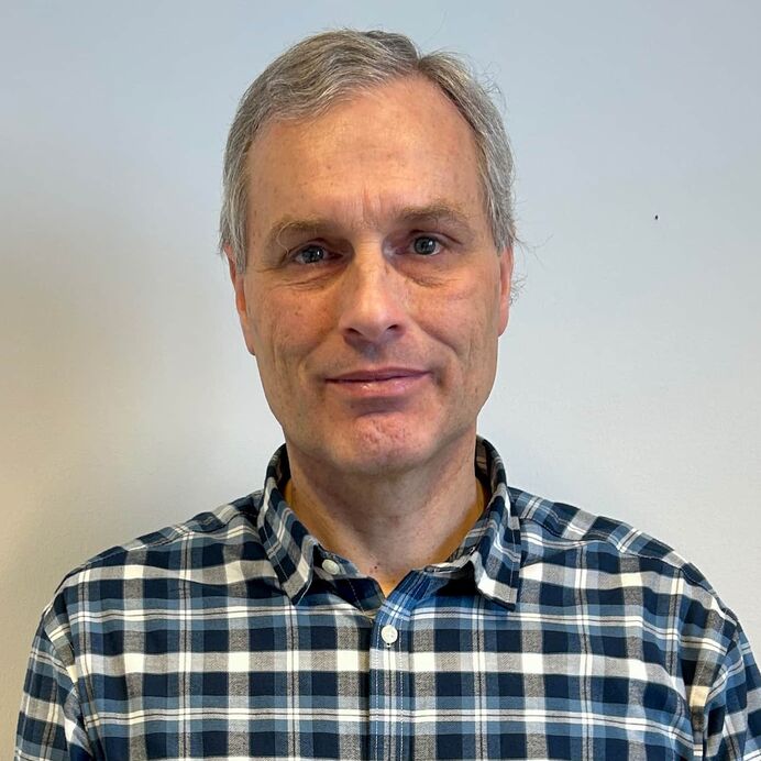 Porträt von Prof. Dr. Friedrich Prall mit grauen Haaren in einem karierten Hemd vor neutralem Hintergrund.