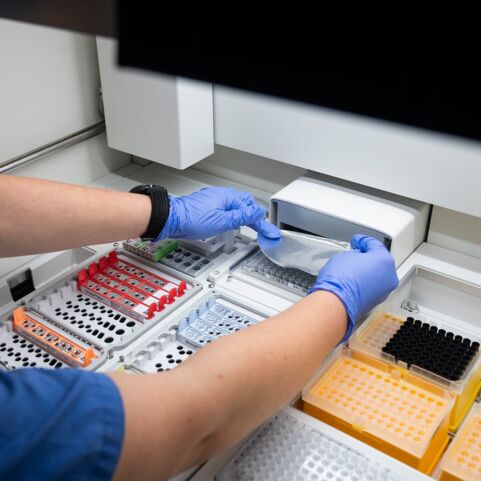 Bestücken eines NGS-Sequenzierers Laborant mit blauen Handschuhen, der Proben in einen NGS-Sequenzierer einsetzt.