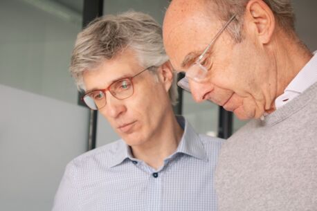 Zwei Männer mit Brille schauen konzentriert nach unten.