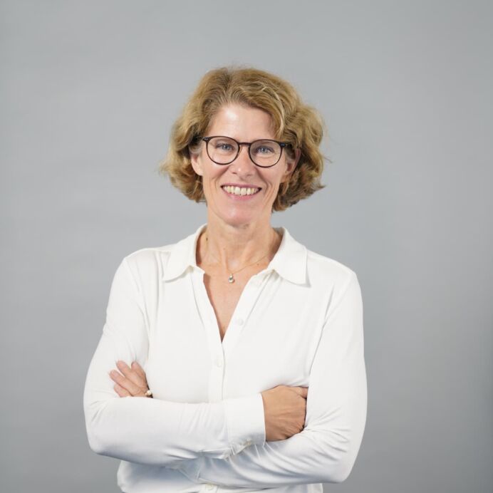 Hämatopathologie Lübeck - Dr. med. Charlotte Wohlschläger - Fachärztin für Pathologie Porträt von Dr. med. Charlotte Wohlschläger. Sie trägt eine weiße Bluse und eine Brille, die Arme sind verschränkt. Sie steht vor einem neutralen Hintergrund.