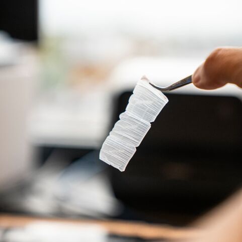 Gewebeschnitt Nahaufnahme einer Hand, die mit einer Pinzette präzise geschnittene Gewebeschnitte hält, die für mikroskopische Analysen vorbereitet wurden.