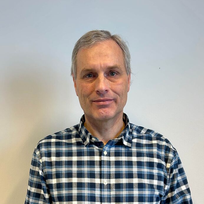 Porträt von Prof. Dr. Friedrich Prall mit grauen Haaren in einem karierten Hemd vor neutralem Hintergrund.